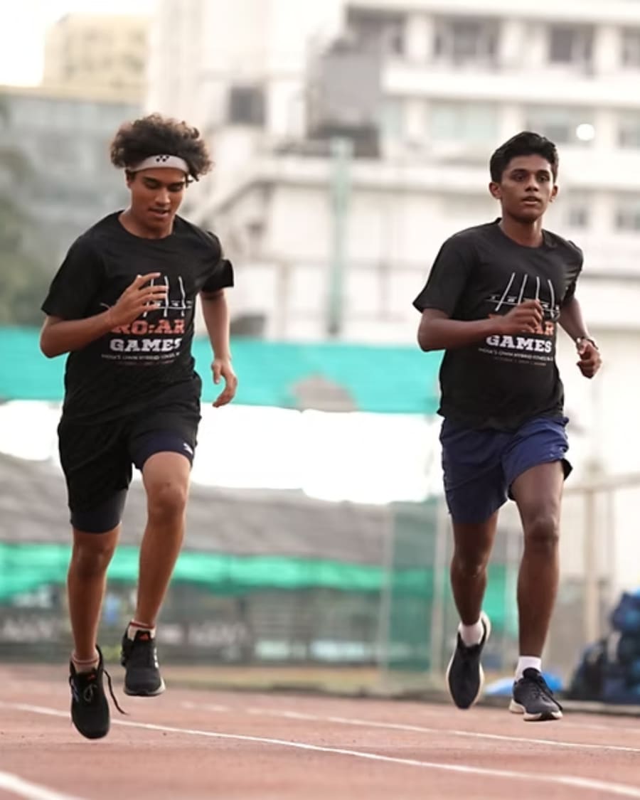 Two younger athletes running together on the track