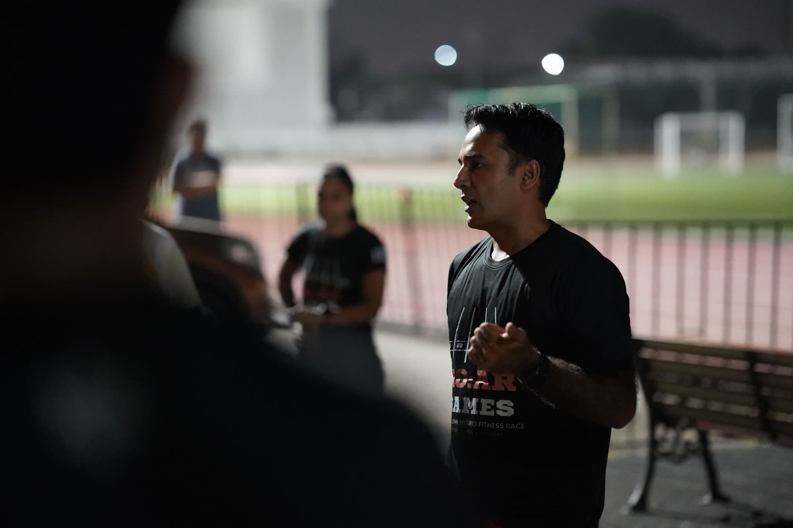 A coach briefing athletes on the track at dusk