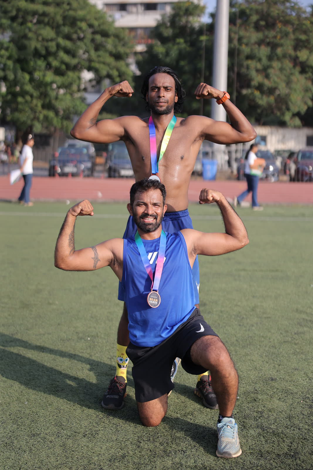 Two finishers flexing with their medals