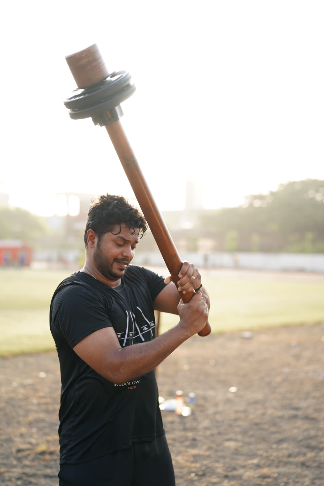 An athlete lifting the R.O.A.R mace overhead at golden hour