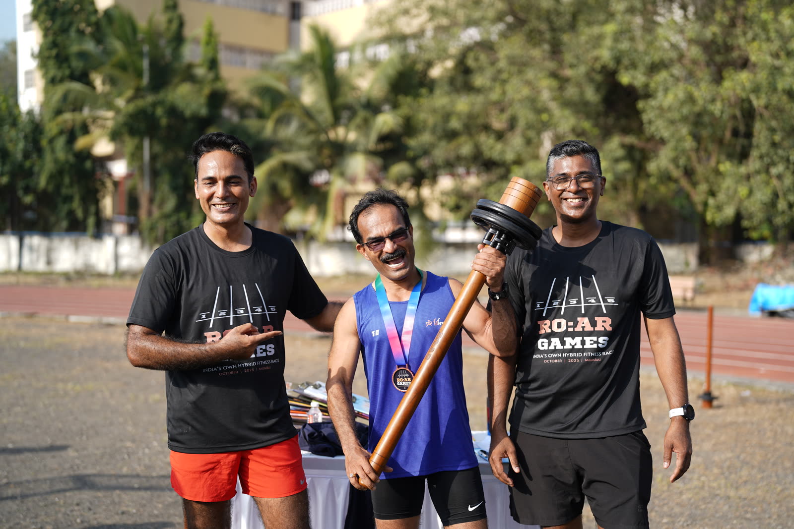 Three athletes posing with the mace trophy