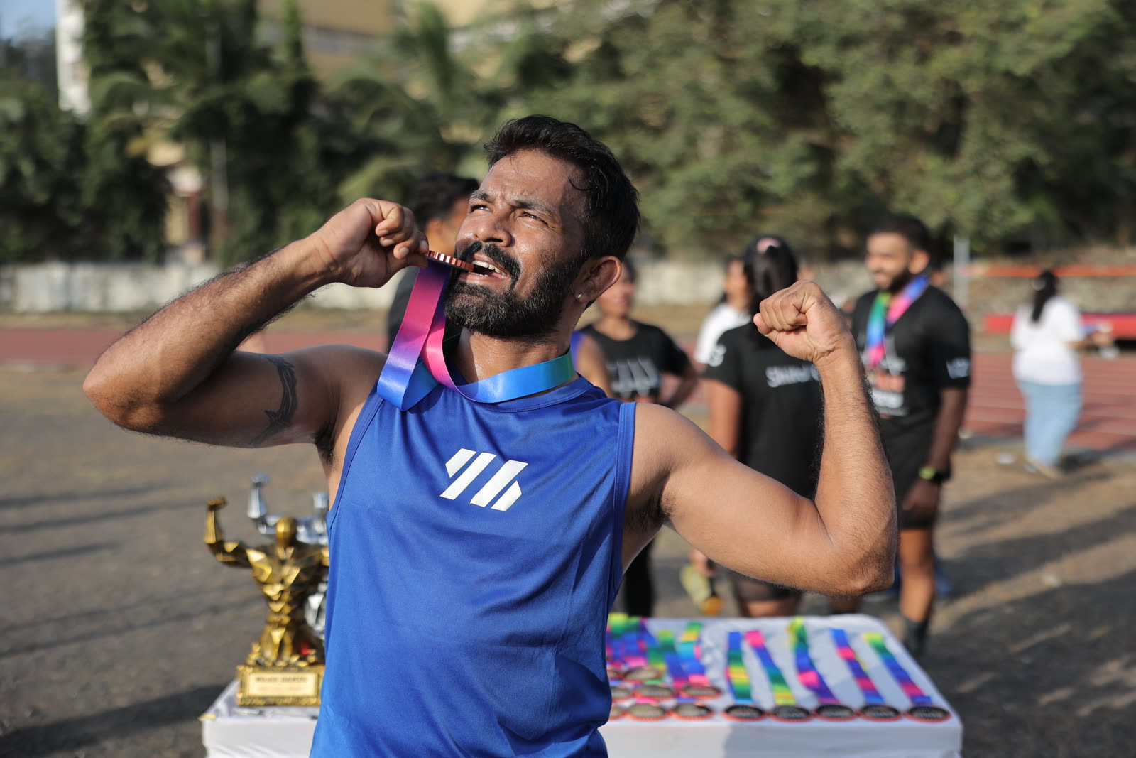 A finisher biting his medal beside his trophy