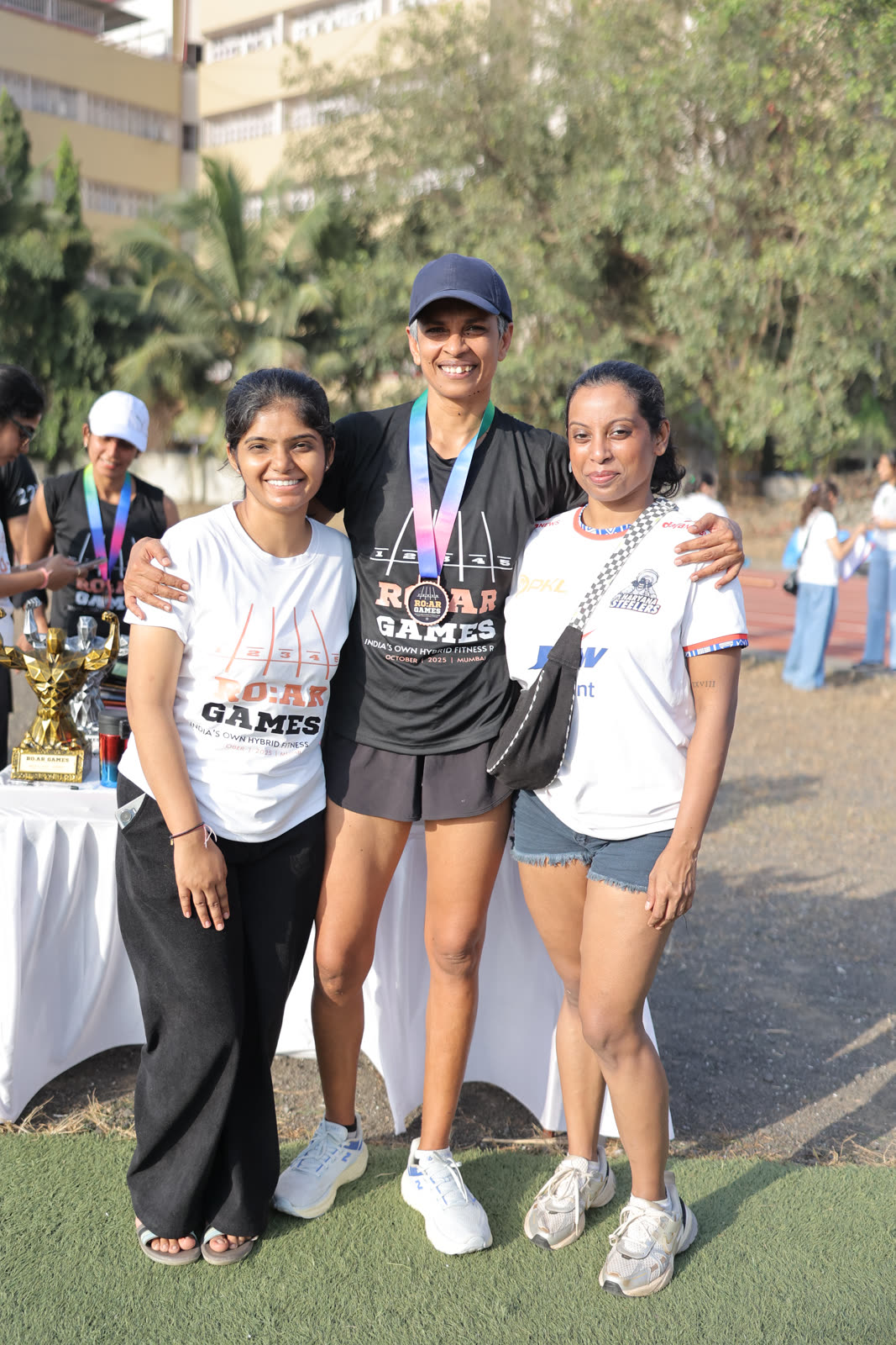 Three finishers posing together, one wearing her medal